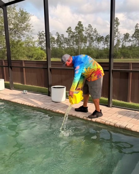 A Goodies Pool Care technician adding treatment to a pool from a jug