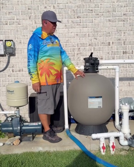 A Goodies Pool Care technician at a pool pump and sand filter