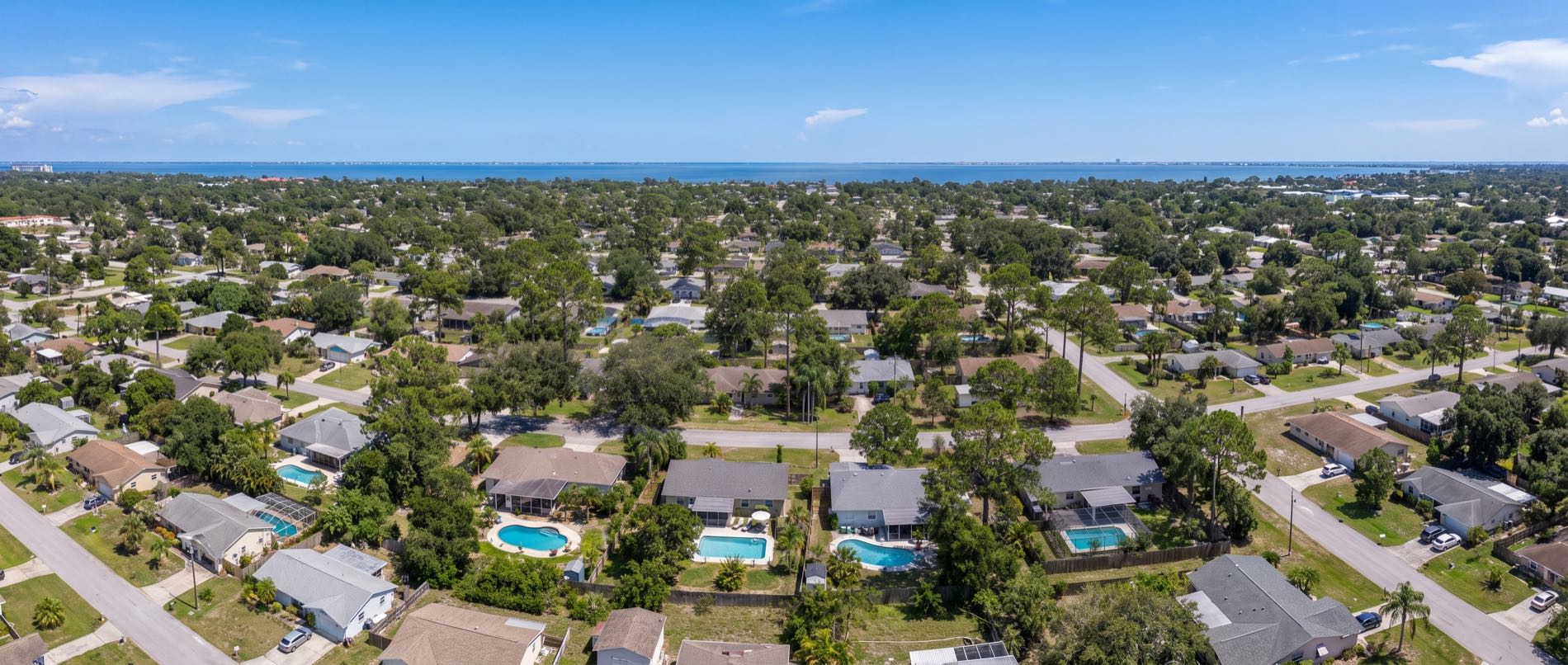A low aerial over Springfield, with small backyard pools behind older modest homes in the foreground and a compact grid of short streets beyond